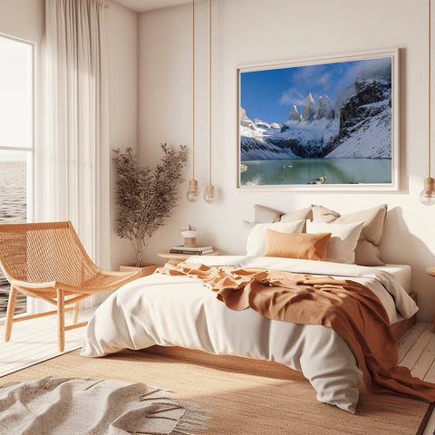 The towering, snow-capped granite peaks of the Torres Del Paine mountain range in Chile, rising dramatically above a serene glacial landscape under a clear sky.