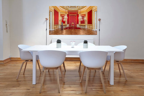 A luxurious interior photograph of a red-walled royal room in the Royal Castle of Warsaw, featuring gold molding and regal furnishings.